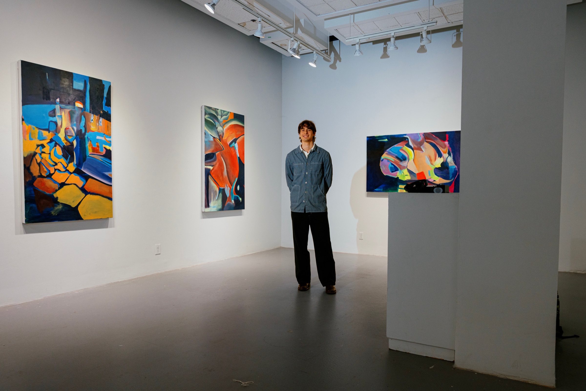 Gabriel Sames standing in the middle of his exhibition Hearing Shapes, surrounded by his paintings